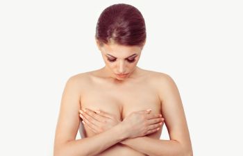 Concerned woman covering her breasts with her hands.