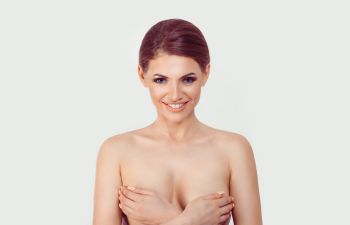 Happy woman covering her breasts with her hands.