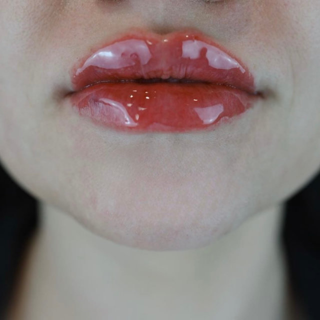 Close-up of a person's slightly parted lips, glossy and wet, with a focus on the texture and shine of the lips.